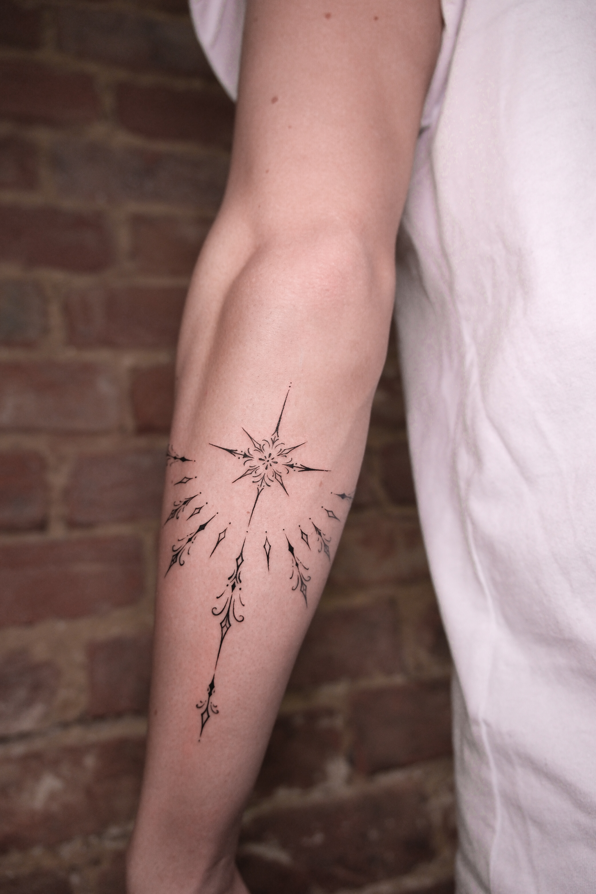 Zartes Fineline Tattoo mit filigraner Blumenranke