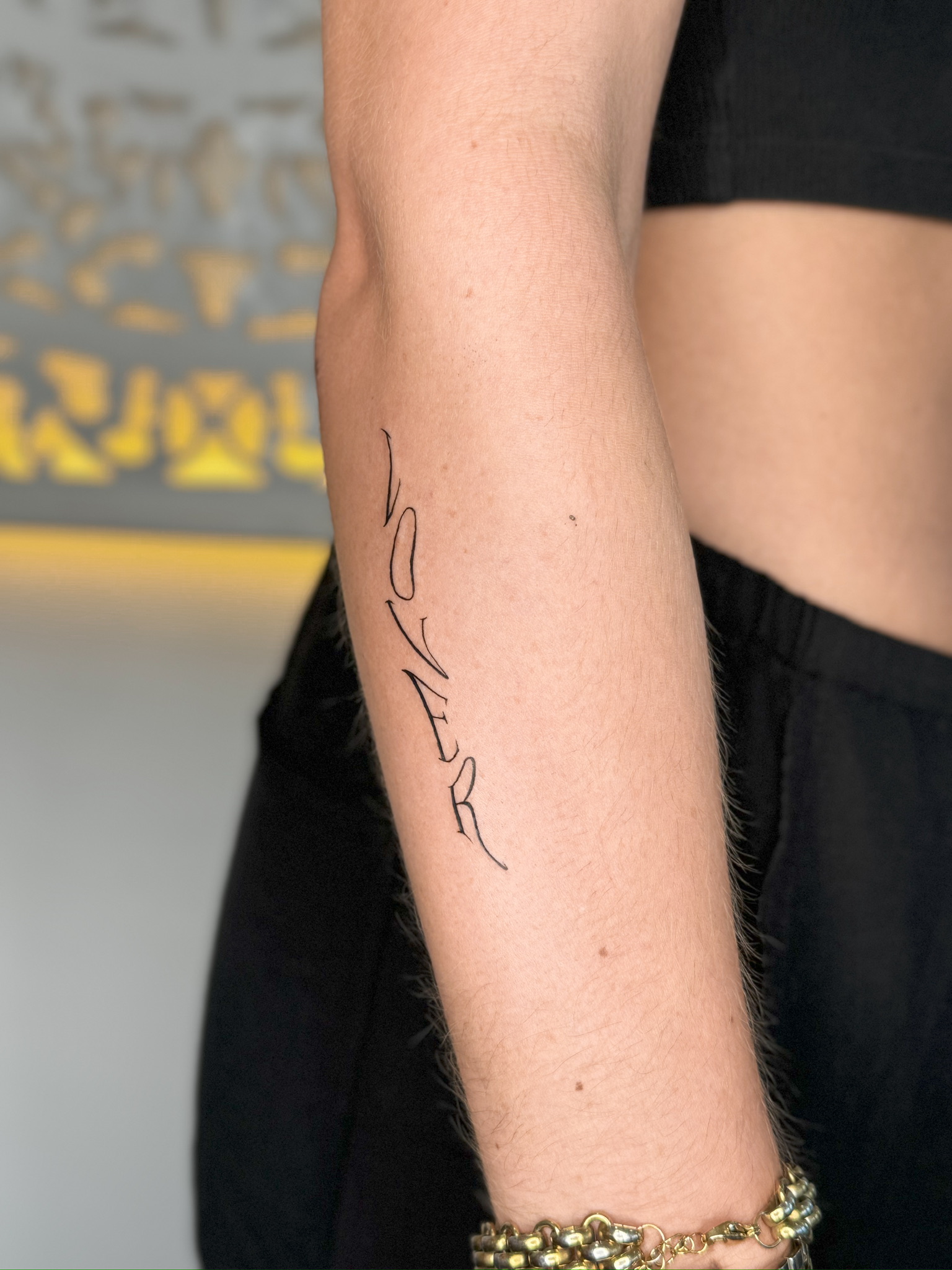 Dezentes Fineline Blüten-Tattoo an der Schulter